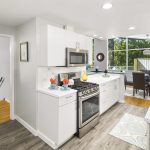The bright, spacious kitchen with a wrap-around eating bar offers plenty of counters and cabinet space, new luxury vinyl flooring, stainless gas range, built-in desk, pantry, and back deck access. 