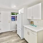 The bright, spacious kitchen with a wrap-around eating bar offers plenty of counters and cabinet space, new luxury vinyl flooring, stainless gas range, built-in desk, pantry, and back deck access. 