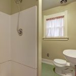 The bathroom serves the home and has enough space in front of the toilet to accommodate a dresser, cabinetry, or other space-efficient options.