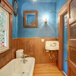 The bathroom features warm wood tones, a clawfoot tub, wainscoting, and...  