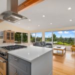 The kitchen boasts a wide-open island concept with quartz countertops, modern cabinetry, stainless appliances, gas range, built-ins, dramatic architectural beam, and...     