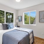 The spacious front bedroom has a treehouse feel with windows on two sides that offer views of the front courtyard and morning light from the east. It is conveniently located across the hall from the shared bathroom.