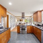 The open kitchen is a chef's delight, featuring stainless steel appliances, a separate veggie sink, and a breakfast bar that flows into the dining area. 