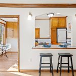 The sun-drenched eat-in kitchen seamlessly connects to the living room’s eating bar, creating a bright and inviting space for cooking, dining, and gathering.