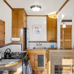 The kitchen is a charming blend of vintage character and function, featuring a built-in hutch with an original leaded-glass window, classic tile countertops and backsplash, and beautifully preserved glowing wood cabinetry. Thoughtful details like an old-fashioned icebox add to its timeless appeal.