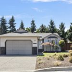 Wide front yard view showcasing mature plantings, fresh mulch, and the home’s inviting single-level design.