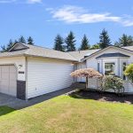 Driveway approach to the generous two-car garage, framed by established greenery and low-maintenance vinyl siding.