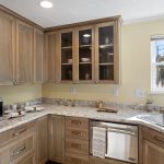 Granite-look Formica surfaces, tile floors, and glass-front cabinetry—durable finishes with subtle charm and plenty of space to work and store.