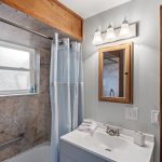 The full bathroom is updated with a modern vanity, soft lighting, and a large window for natural light—simple and clean, with timeless finishes.