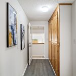 This second hallway connects the kitchen to the lower-level flex space and adds serious function with a full wall of oak cabinets, a second coat closet, and matching LVP flooring.