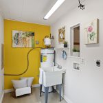 Tucked off the flex room, the dedicated laundry area features cheerful light, a utility sink, and hookups for a side-by-side washer and dryer. A sunny window brightens the chore zone, while a bold pop of color adds personality and warmth.