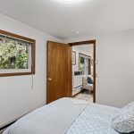 The cozy north bedroom features fresh carpet, ample closet space, and a peaceful view toward the private parking area.