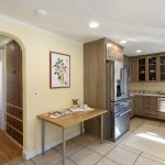 The refreshed kitchen opens into a bright living space—laminate flooring currently in place, with real hardwoods beneath ready for renewal.