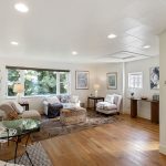 Framed by wide windows and a leafy backdrop, the living space feels gently elevated—tucked into the trees with quiet separation from the street.