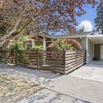 One last look from the practical side: attached covered parking sits right beside the house, while the fenced front garden keeps the arrival feeling residential rather than driveway-first.