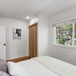 The wide front window looks into the garden canopy, giving the room a leafy outlook and some visual distance from the street.