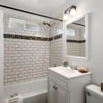 The tub was refinished for launch, with a full subway-tile surround, frosted window for daylight and privacy, and a large linen cabinet just out of frame for towels and bath storage.