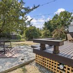 Out back, the lot breaks into places to actually use it: deck, separate patio, open yard and a mature tree tying the whole thing together.