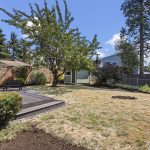 The backyard has room to spread out—open ground through the middle, mature planting around the edges, and the shed tucked out of the way at the far end.