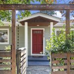 Some houses earn the straight-on shot. Here, the jasmine arbor, gate and red door line up into a front approach worth framing.
