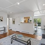 From the living room, the whole plan reads front to back in one glance—kitchen, dining, then deck and backyard beyond.