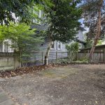 The shared backyard is fully fenced and shaded by mature trees, with paved areas for outdoor seating.