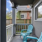 The shared covered porch fits two chairs—a small sitting spot just outside the front door.